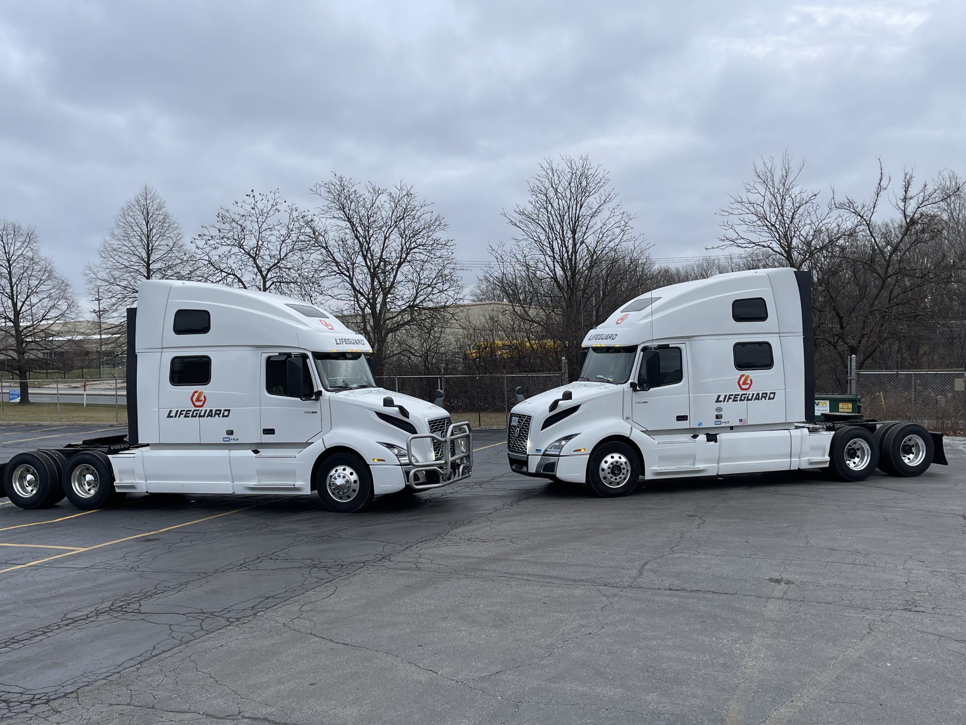Two white Lifeguard Volvo VNL tractors parked side by side